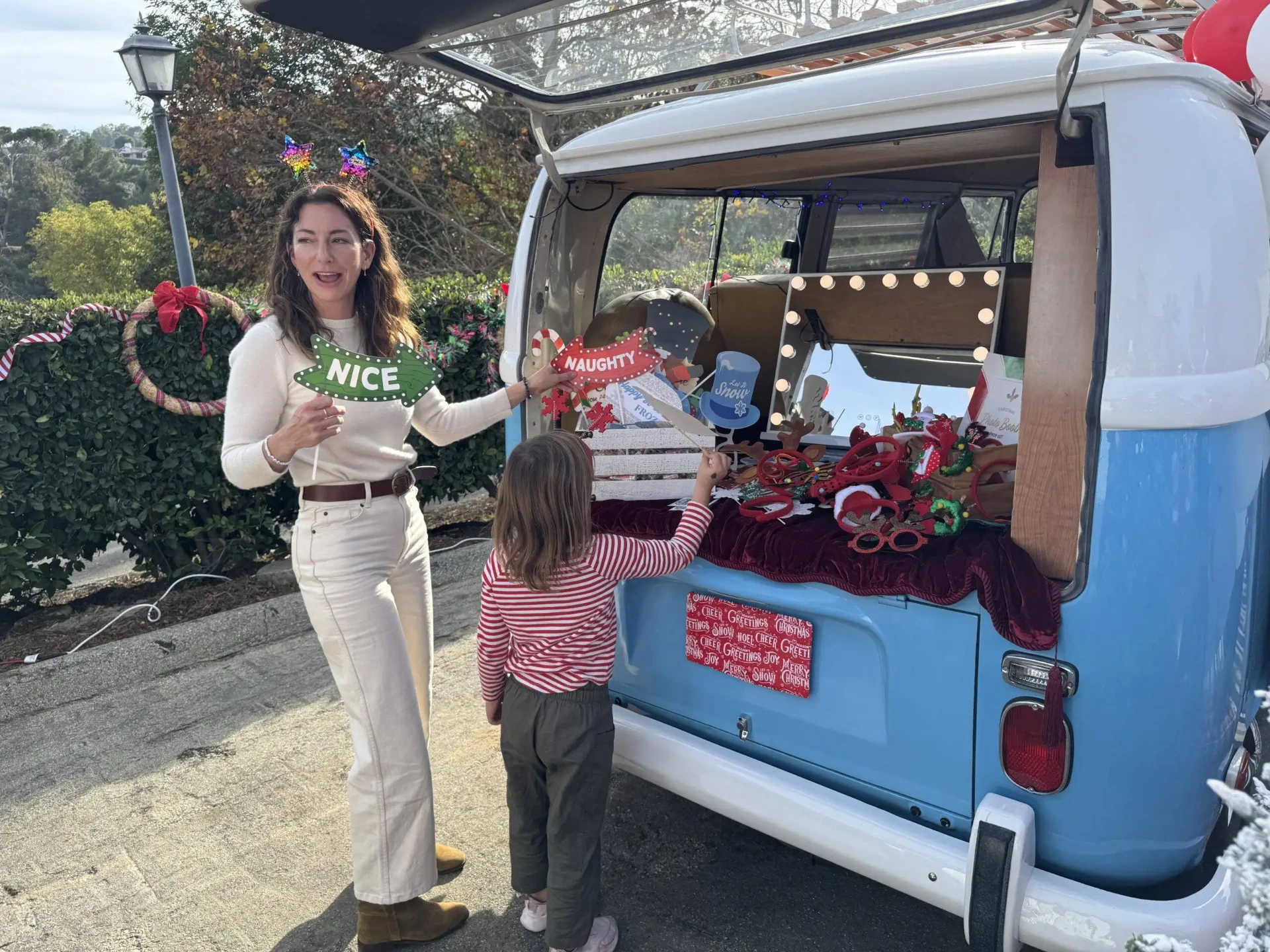 Attendant handing photo booth props to a young guest at the open back hatch of the Photobus