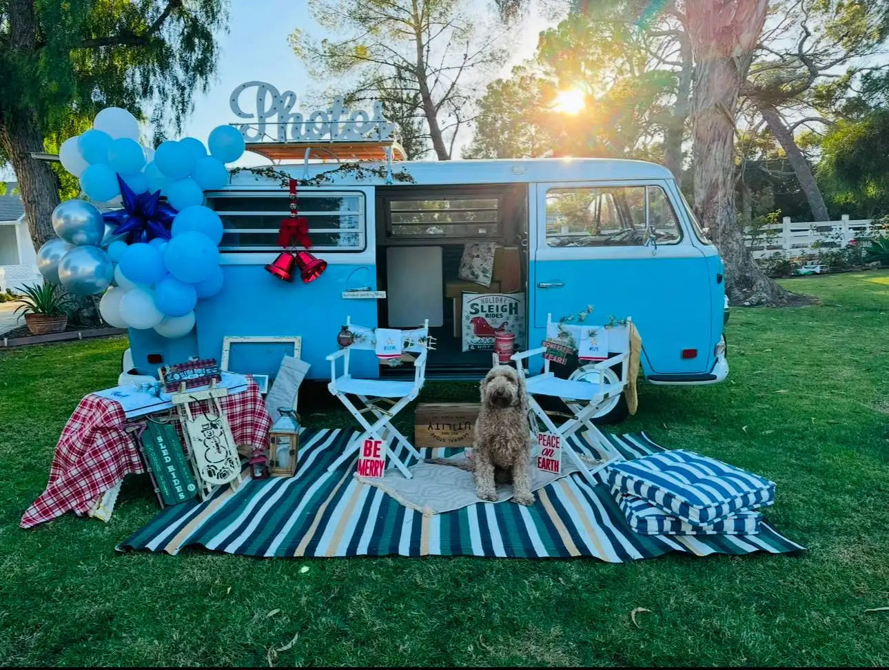 The Photobus at golden hour with balloon garland, director's chairs and a golden doodle sitting on the striped rug