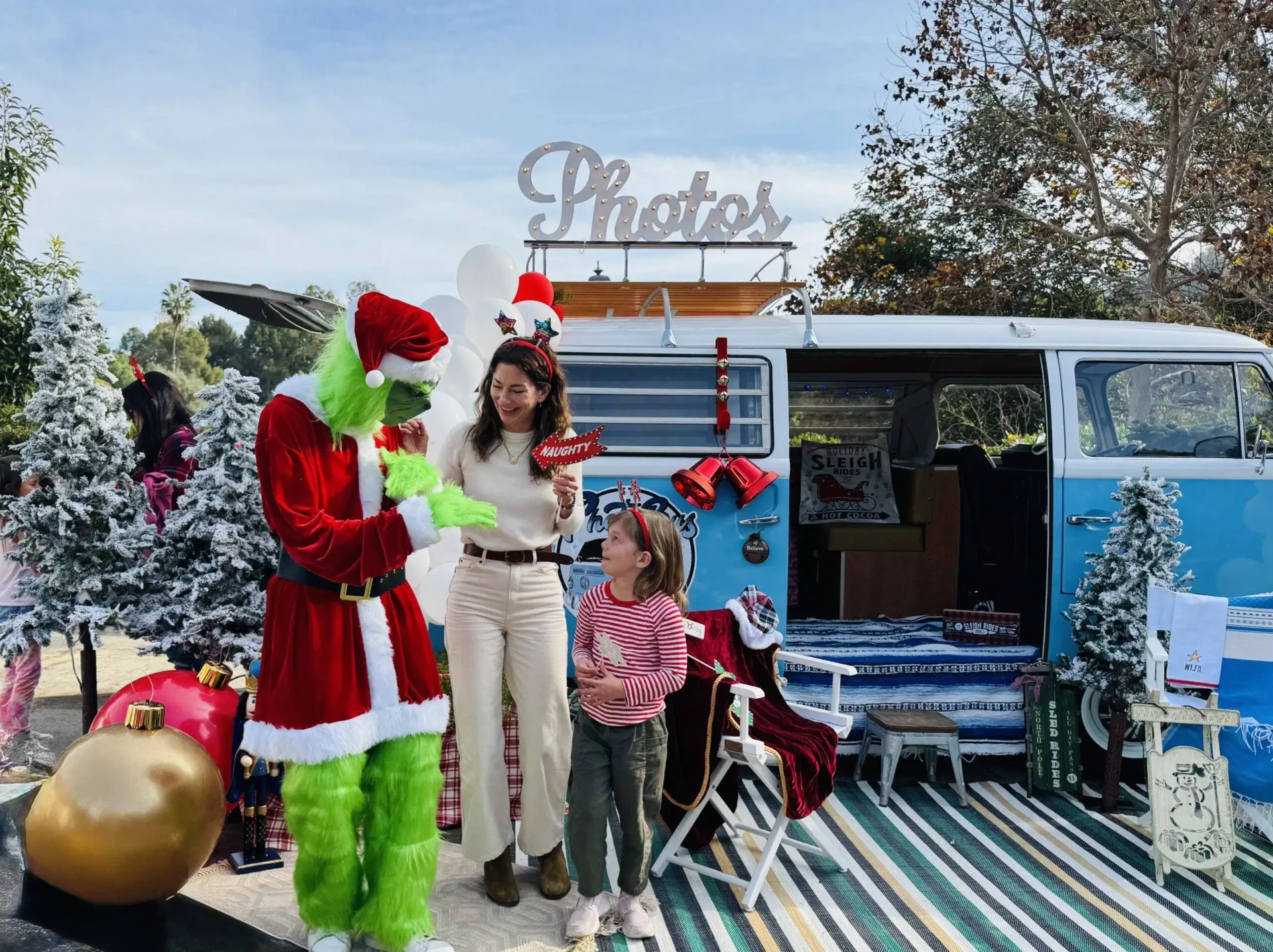 Guests laughing with a costumed character beside the Photobus under a lit Photos marquee sign